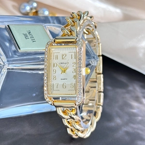 Macro view of gold chain link watch strap with diamond bezel and white rectangular dial