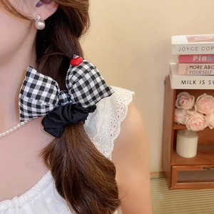 Detail of gingham bow scrunchie with red heart ornament on model hairstyle