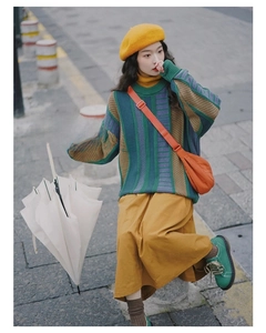 Detailed view of an orange nylon dumpling bag styled with a retro knit sweater outfit