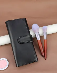 Gros plan sur la pochette à pinceaux en cuir noir avec bouton pression et manche en bois