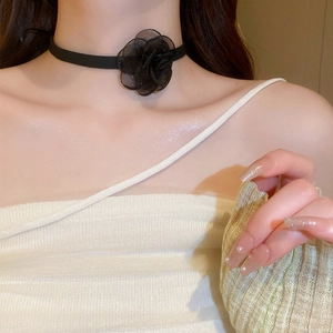 Macro shot of a black fabric floral choker necklace worn on a woman's neck