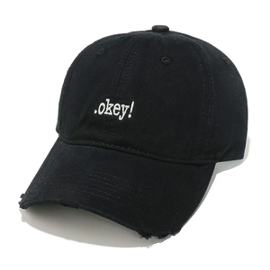 Detailed close-up of black cotton baseball cap with white Okey embroidery and frayed brim
