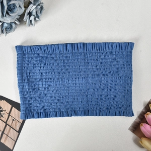 Detailed view of blue ruched bandeau top with elastic texture on gray background