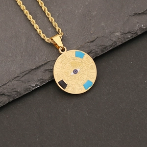 Gold evil eye pendant necklace with blue enamel on textured stone background