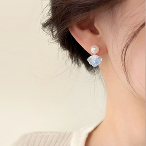 Detail showing elegant pearl and blue textured resin drop earrings on a model's ear