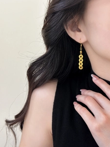 Close-up of model wearing triple-layered gold coin drop earrings in vintage style