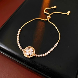 Macro view of adjustable gold-plated tennis bracelet with zircon clover and pull-string clasp