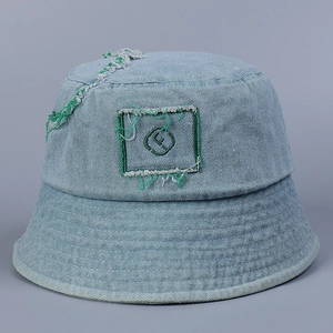 Detailed macro view of light blue denim bucket hat with green embroidery and frayed edges