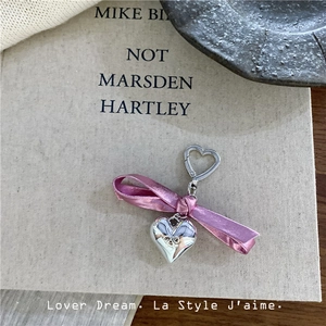 Detail of silver heart charm with pink satin bow on aesthetic book background