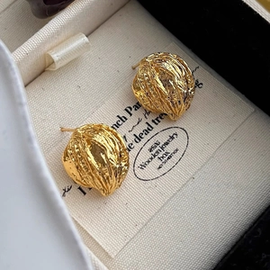 Close-up of golden vintage stud earrings with pleated texture in a premium jewelry box