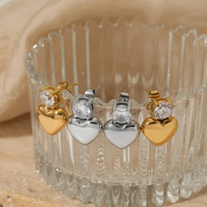 Gold and silver heart earrings with sparkling cubic zirconia on a clear glass edge