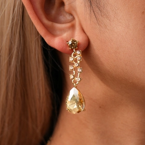 Close-up of champagne teardrop drop earrings with gold plating and sparkling gemstones