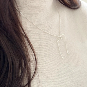 Close-up of 925 sterling silver bow knot necklace on a light knit sweater