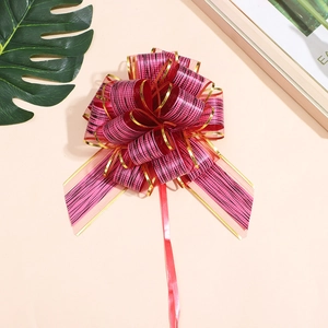 Detail view of large red Christmas gift bow with gold edges and black tree bark stripes