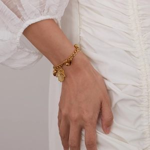 Close-up of a gold Hamsa Hand charm bracelet on a woman's wrist in elegant style