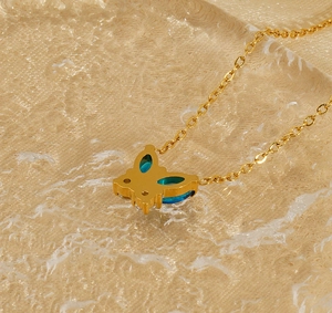 Vue macro d'un collier papillon en or 18 carats avec cristaux bleus sur fond doré