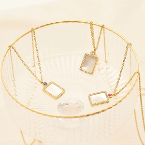 Detailed shot of three gold necklaces with rectangle shell pendants and colored zircons