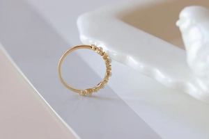 Close-up of a slim gold ring with delicate alternating pearls and small crystals