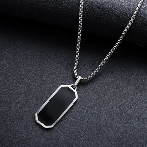 Dettaglio di una catena d'argento con pendente rettangolare nero su trama in pelle