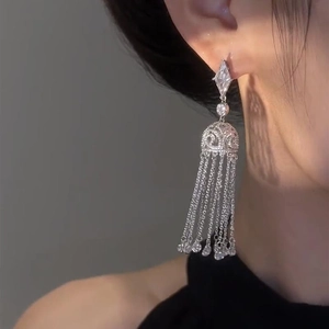 Elegant silver diamond-encrusted geometric tassel earrings worn by a model on white background