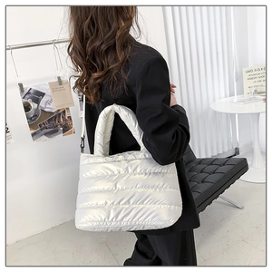 Detailed view of white quilted puffer bag with metallic finish and padded handle