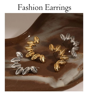 Detailed view of leaf shaped C-stud earrings in gold and silver finish on ceramic