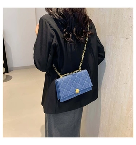 Blue denim quilted square bag with gold chain strap worn by a model in casual attire
