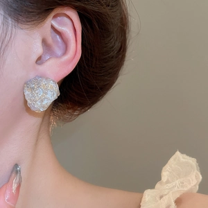 Close-up of irregular silver and purple resin stud earrings with crinkled metallic texture
