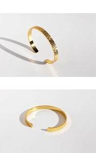 Dettaglio della trama a strisce verticali su un bracciale dorato minimalista aperto