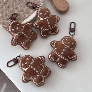 Close-up of plush gingerbread man keychains with white embroidery and metal hooks