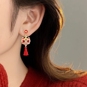 Boucles d'oreilles lion avec pompon rouge et plaqué or portées par un mannequin