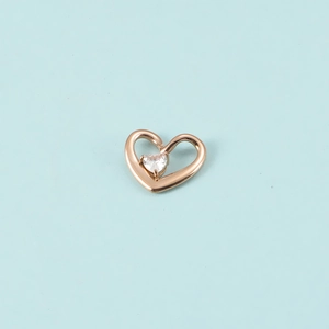 Gros plan du pendentif cœur en or rose avec une pierre étincelante sur fond bleu