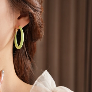 Close-up of lime green matte round hoop earring with gold clasp on model's ear