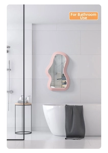 Pink wave-shaped wall mirror with modern wavy frame hanging in a bright bathroom setting