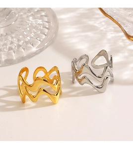 Detail of wavy crisscross stackable rings in gold and silver finish on reflective surface