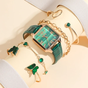 Detail of emerald square watch with gold butterfly bracelets on elegant display