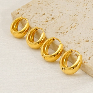 Macro shot of 18k gold plated chunky teardrop hoop earrings on a stone background