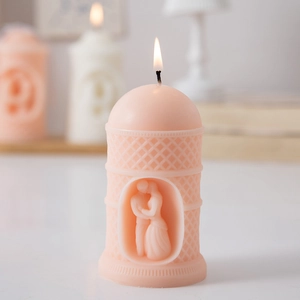 Detailed relief candle in pink with couple carving and burning flame in home setting