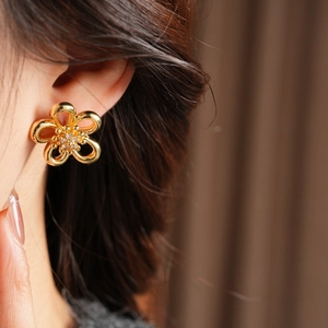 Detailed view of hollow flower stud earrings with gold plating and cubic zirconia