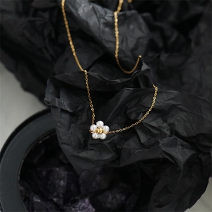 Detailed macro view of white pearl daisy pendant on 18K gold plated necklace