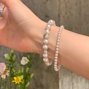 Détail de bracelets en perles superposés avec perles en strass sur un fond texturé