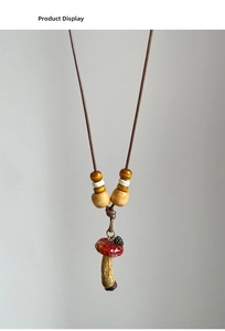 Macro shot of red resin mushroom pendant with small metal pinecone and wooden beads