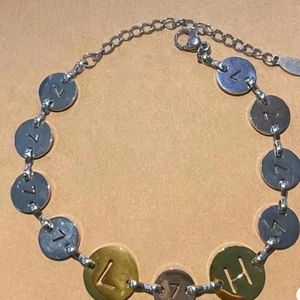 Dettaglio del bracciale a catena in acciaio bicolore con ciondoli traforati con lettere