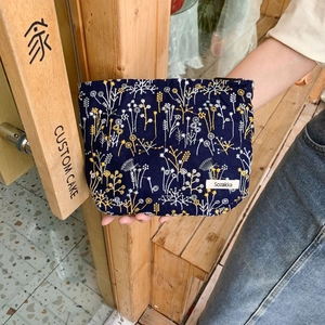 Detailed close-up of floral embroidery on a dark blue fabric makeup organizer bag