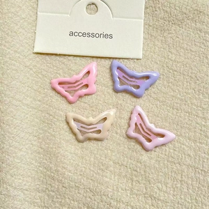 Macro shot of 4 colorful butterfly-shaped hair clips in pastel pink, purple, and beige tones