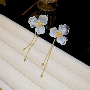 Macro detail of white marble petals and gold tassels on elegant floral earrings