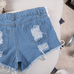 Dettaglio di shorts in denim azzurro con lacci laterali ed estremità dell'orlo sfrangiate
