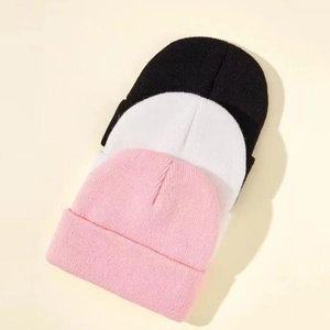Detailed knit texture of classic black, white, and pink beanies for kids' autumn wear