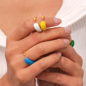 Detailed view of colorful enamel teardrop rings on fingers with adjustable gold finish