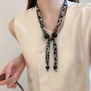 Détail du collier noeud en tissu léopard avec perles porté par un mannequin
